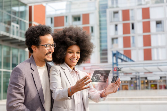 Business couple using futuristic transparent glass digital tablet in city