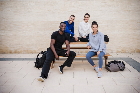 Smiling sports people sitting together on bench