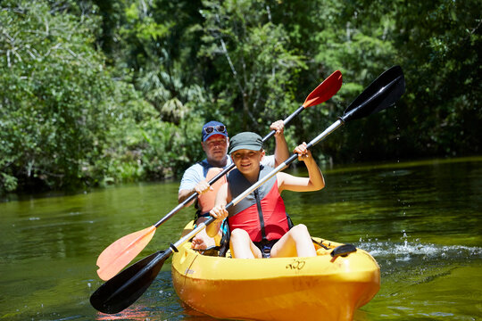 Smiling girl with father canoeing with oar in lake