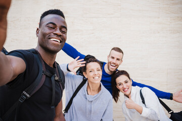 Cheerful athlete friends taking selfie in front of wall