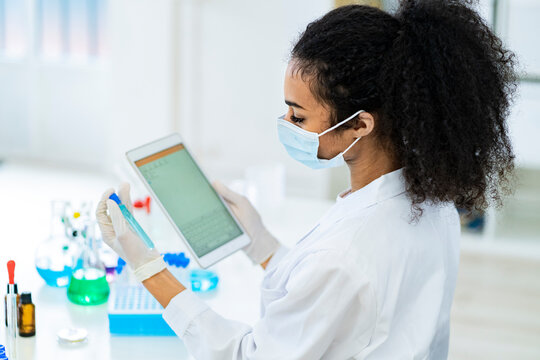 Researcher looking at test tube and digital tablet while working in laboratory