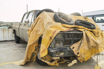 Abandoned pickup truck covered with a yellow tarpaulin at a car park