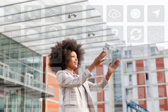 Businesswoman looking on map over futuristic transparent digital tablet with icons around outdoors