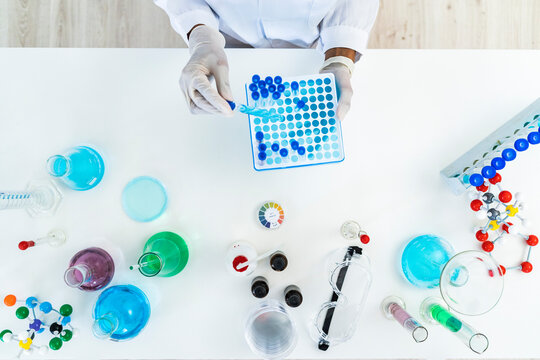 Female researcher removing test tube from microplate on table in laboratory
