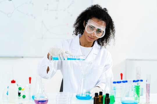 Female researcher pouring liquid in flask while experimenting at laboratory