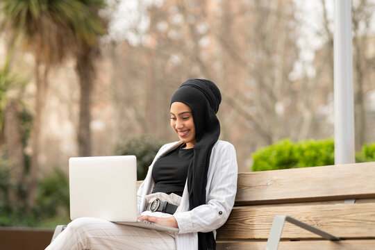 Beautiful Arab businesswoman working on laptop while sitting outdoors