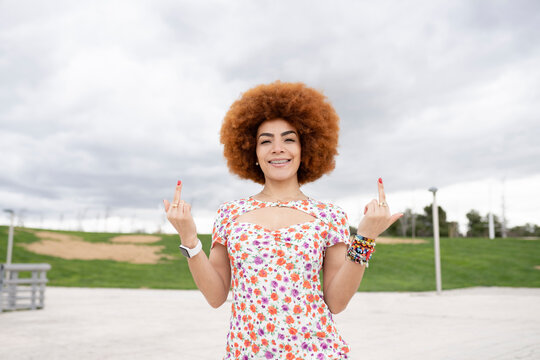 Smiling woman gesturing obscene hand sign at park