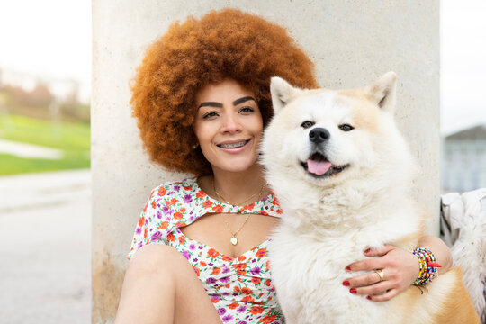 Redhead woman smiling while sitting with dog in front of pillar