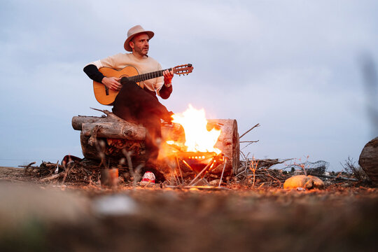 Mature man playing guitar against sky