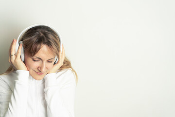 Fototapeta premium Portrait of smiling pretty woman enjoying music with white headphones on white background