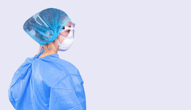 Profile Photo Of A Female Doctor In A Coat, Goggles And A Mask. The Doctor Fights The Spread Of The Covid 19 Virus. Gray Background And Side Space.