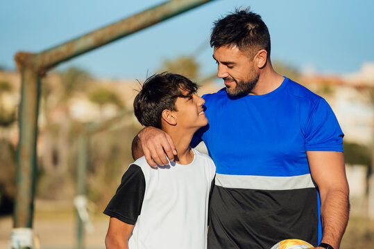 Smiling father with arm around neck of son at sports court