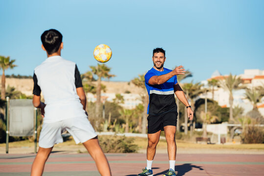 Father and son practicing with soccer ball on sports court