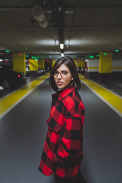 Young woman with eyeglasses standing at underground parking lot