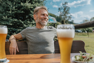 Smiling mature man looking away while sitting in beer garden