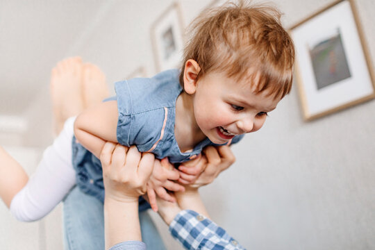 Playful mother lifting cheerful daughter while spending leisure time at home