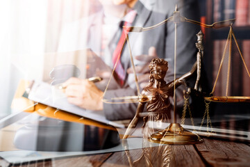 Obraz premium Justice and law concept.Male judge in a courtroom with the gavel, working with, computer and docking keyboard, eyeglasses, on table in morning light