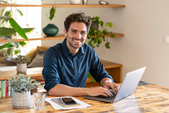 Happy male freelancer working from home through laptop