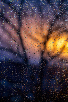 Raindrops on window pane at sunset