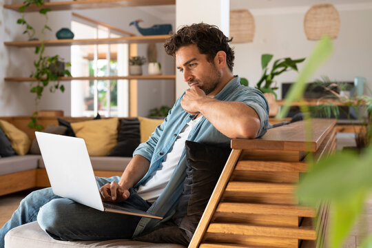 Concentrated freelance worker using laptop while sitting on couch at home