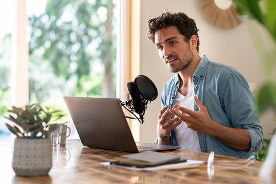 Male freelance worker looking away while podcasting at home office