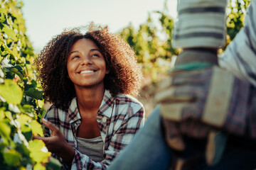 Mixed race female farmer smiling at male colleague while enjoying working on beautiful farm