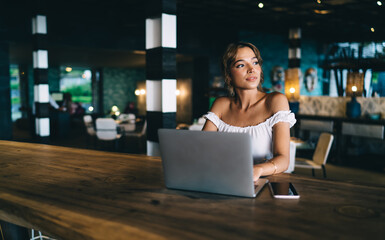 Positive woman using laptop in modern cafe