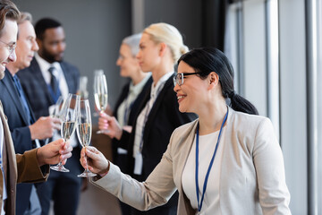 happy multiethnic business partner clinking champagne glasses during conference