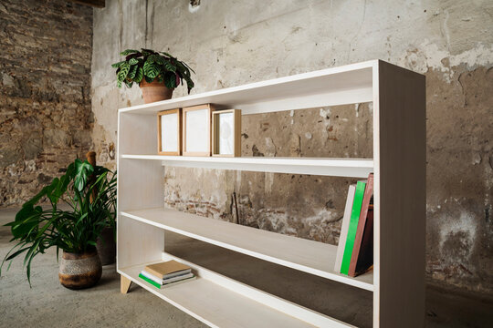 Few books and picture frames on mostly empty wooden bookshelf