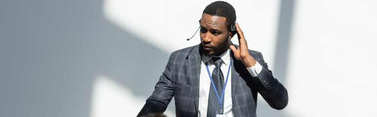 african american lecturer adjusting headset during seminar, banner