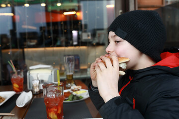 Boy eating burger on restaurant terrace