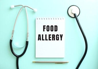 On a blue background, a stethoscope and a white notepad with the words FOOD ALLERGY.