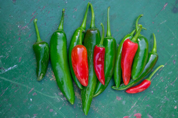 Capsicum annuum Jalapeno chilli hot peppers, group of green and red fruits on wooden colorful table background