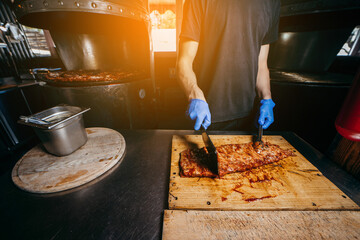 Male butcher or chef is preparing prime rib steaks from a large beef rib roast.