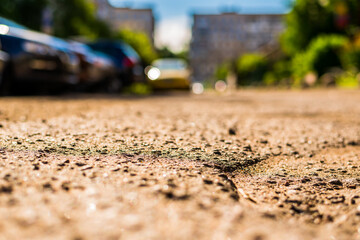 Sunny day in a city, bad road in city courtyard with parked cars. View from the asphalt level