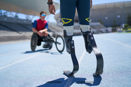 Male amputee and wheelchair athletes on sunny blue sports track
