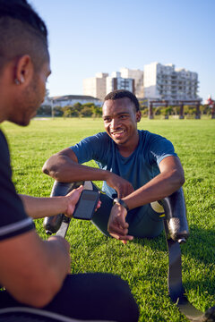 Coach talking with young male amputee athlete in park