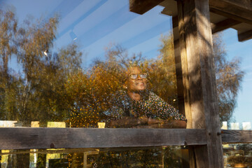 Thoughtful woman looking up at trees from restaurant window