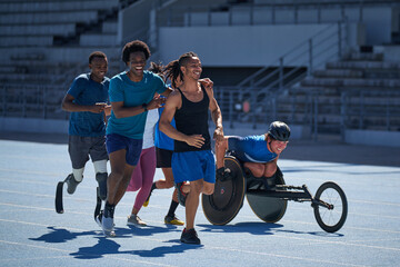Happy diverse athletes running on sunny sports track