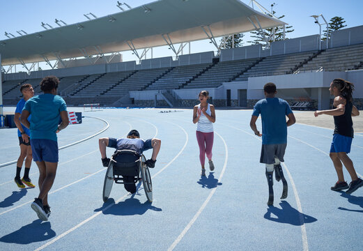 Young diverse athletes warming up on sunny blue stadium sports track