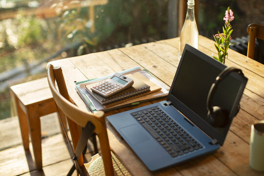 Laptop, headphones, calculator and notebooks on cafe table
