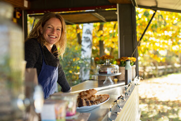 Portrait happy female food cart owner working in park