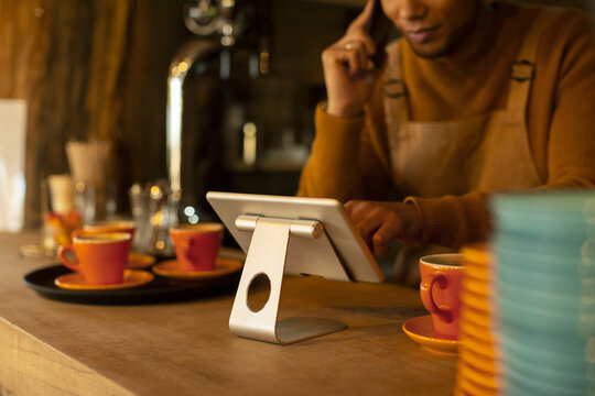 Male barista using digital tablet at cafe counter