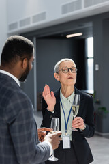 middle aged businesswoman gesturing while talking to african american colleague on conference