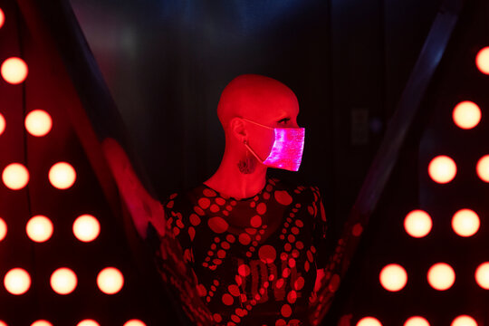 Portrait stylish woman with shaved head wearing shimmery face mask