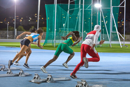 Female track and field athletes taking off at starting block