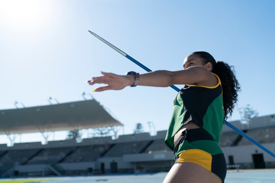 Focused female track and field athlete throwing javelin in stadium