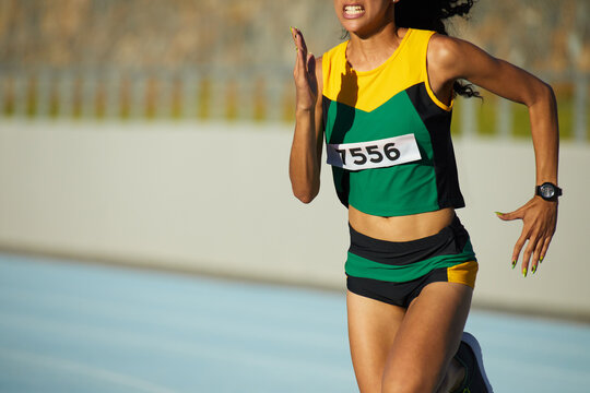 Determined female track and field athlete running in competition