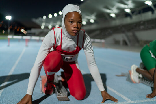 Focused Female Track And Field Athlete In Hijab At Starting Block