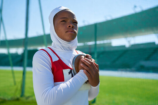 Determined female track and field athlete preparing to throw discus - Powered by Adobe